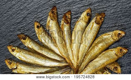 arrangement with lots of fresh smoked sprats on dark stone slab