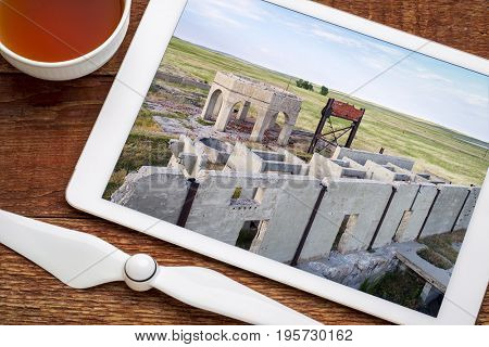 concrete ruins of one of five reduction plants and pump stations manufacturing potash during World War I near Antioch, Nebraska, reviewing aerial image on digital tablet