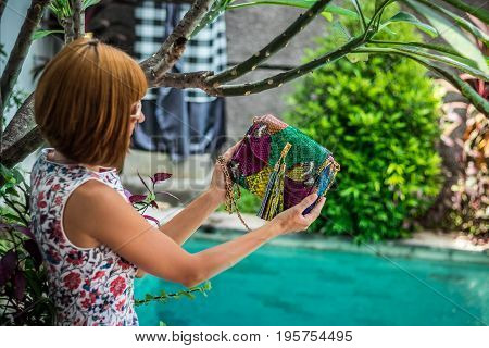 Summer portrait of a beautiful sexy girl with sunglasses and luxury handmade snakeskin python handbag in the swimming pool. Fashion outdoor. Tropical Bali island.