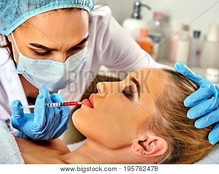 Filler injection for female forehead face. Plastic aesthetic facial surgery in beauty clinic. Cropped shot of doctor in medical gloves with syringe injects lips augmentation. Preservation of youth.