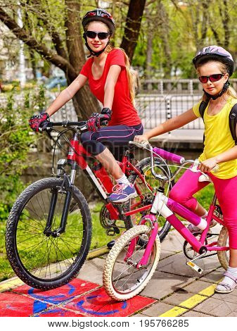 Family bike ride. Mother and daughter wearing bicycle helmet with rucksack . Children biking on yellow bike lane. Bike share program save money and time. Friendship between children of different ages.