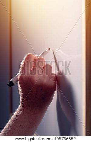 School teacher writing on classroom whiteboard during the lecture selective focus