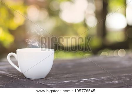 White cup morning coffee in garden and sunrise.