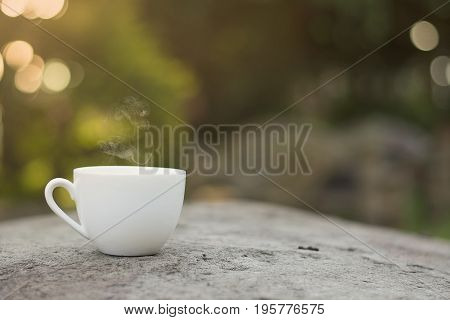 White cup morning coffee in garden and sunrise.