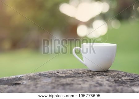 White cup morning coffee in garden and sunrise.