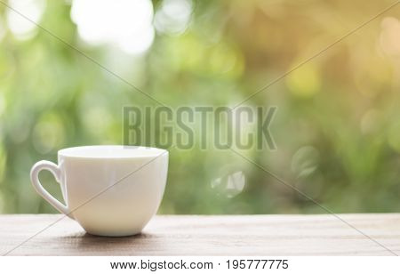 White cup morning coffee in garden and sunrise