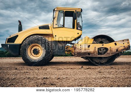 Vibratory Soil Compactor During Highway Construction. Industrial Roadworks With Heavy-duty Machinery