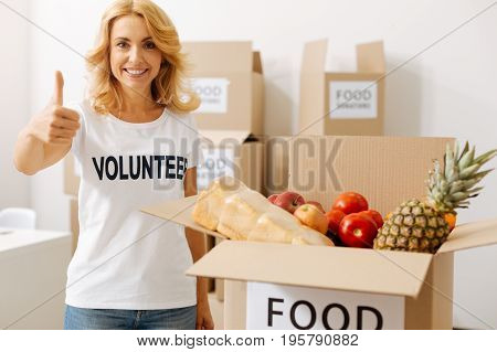 Kind heart. Charming emotional pretty lady offering her help pro bono while packing parcels with food which people donating for those in need