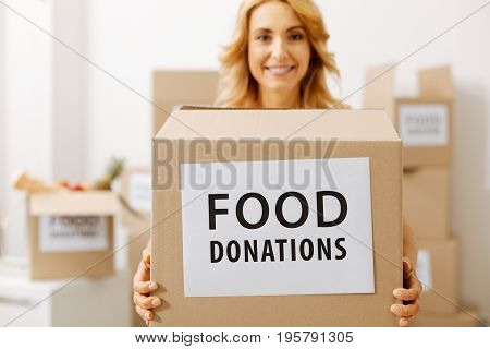 Noble intentions. Altruistic active cute woman holding a box full of food she wanting sending to those in need