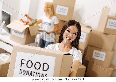 Joining the charity. Devoted passionate wonderful girl helping as a volunteer and collecting packages with donations while sending out food to those in need