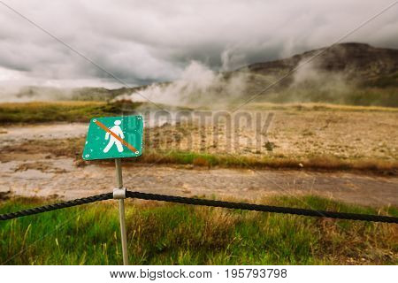 Warning sign of not crossing over rope fence.Caution of high temperature on golden circle tour near big geyser geothermal area.Steaming and boiling acid water and ground.Tourist attraction of eruption