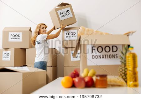 So many boxes. Vibrant clever nice lady needing another box for fitting all the food in it while preparing a shipment for those in need