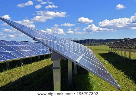 Solar panels on field. Clear sky with a few small clouds on background.