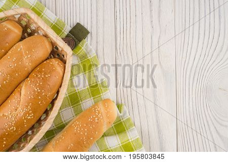 Buns in a wicker basket on old wooden table. Top view.