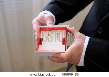bride and groom show wedding bands and wedding bouque
