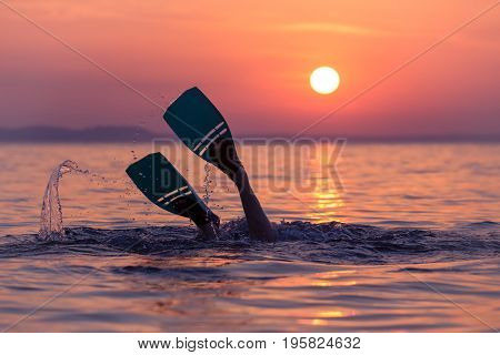 Close up of scuba diver feet with snorkel fins start diving at sunset