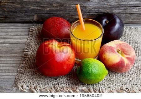 Fresh fruits and a glass of juice.Multi fruit juice.Juice mix fruit on burlap cloth on wooden table.Healthy drink or diet concept.