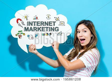 Internet Marketing text with young woman holding a speech bubble on a blue background