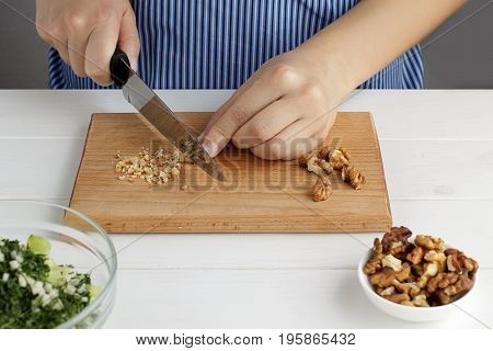 Step By Step Recipe For Tarator. Hands Cut A Walnuts On Board In The Kitchen.