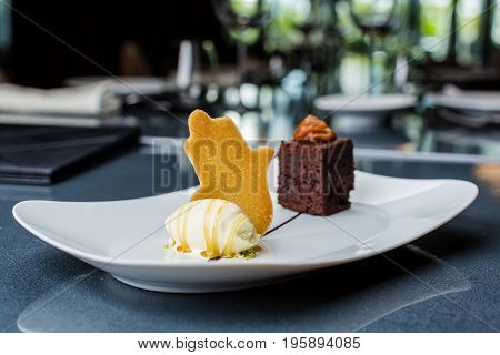 One scoop of the ice cream served on the white plate with brownie and buscuit