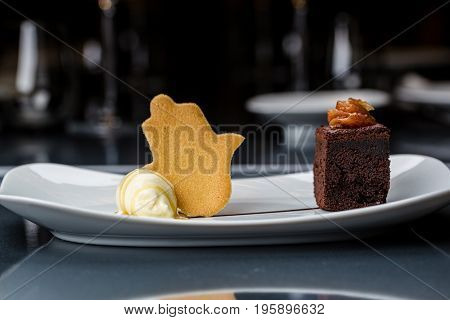 One scoop of the ice cream served on the white plate with brownie and buscuit