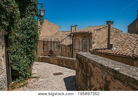 View of typical stone houses with sunny blue sky, in an alley of the historical village of Ménerbes. Located in the Vaucluse department, Provence-Alpes-Côte d'Azur region, southeastern France