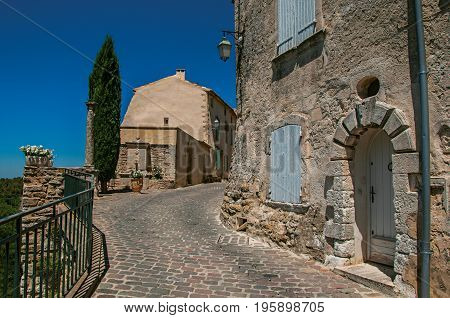 View of typical stone houses with sunny blue sky, in an alley of the historical village of Ménerbes. Located in the Vaucluse department, Provence-Alpes-Côte d'Azur region, southeastern France