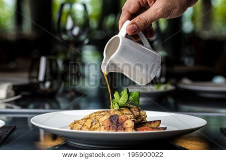 Grilled chicken fillet served with french fries, asparagus and cherry tomatoes, decorated with grilled garlic and baby spinach