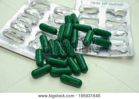 Medicine green  pills or capsules and aluminum foil blister on  white background with copy space.  treatment medication