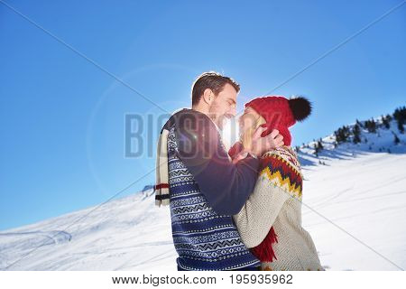 Loving couple embracing in winter park. They put colored caps and scarves