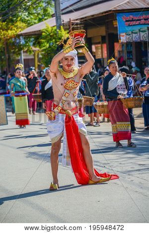 CHIANGMAI THAILAND - JANUARY 25 2015: Dancer man with traditional costume holding tray with pedestal of flower dancing in parade of 22nd Traditional Skirt Fabric and The Indigenous Product and Culture Festival in Mae Chaem Chiangmai Thailand