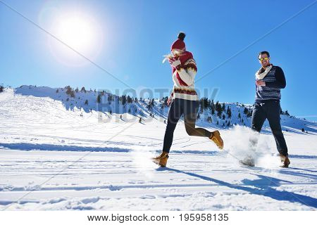 Cheerful young couple having fun in winter park.
