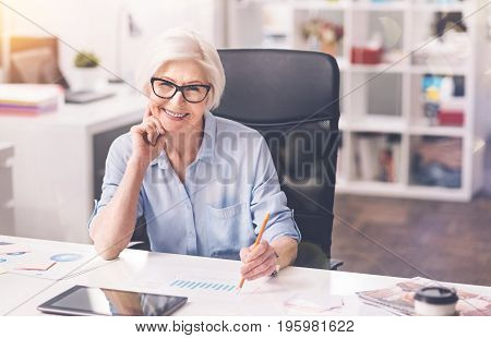 A way for success. Classy competent mature woman working at the office and analyzing a report and sales while thinking about new economic strategy