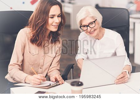 And these are the numbers. Classy lively senior lady doing a presentation on her developments while demonstrating some pictures using her computer