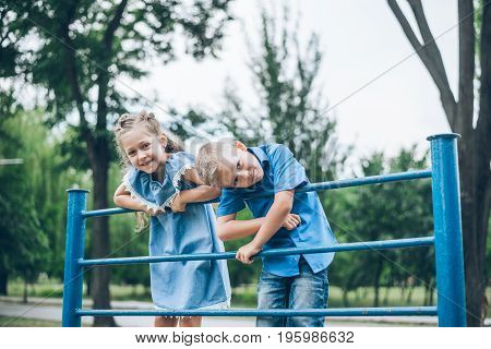 Happy children play on horizontal bar in summer park