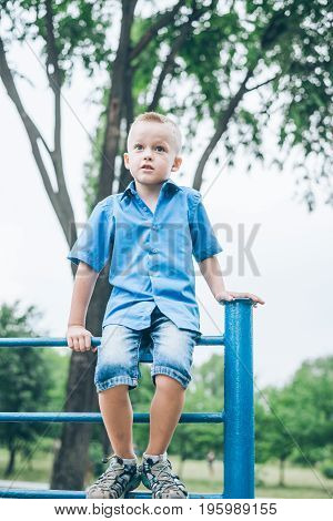 kid playing on horizontal bar in summer park