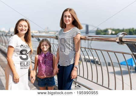 Samesex lesbian family with child on a walk in the park near the river. Lesbians mothers with adopted child, happy family, pregnant couple with kid