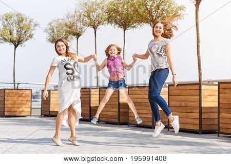 Samesex lesbian family with child on a walk in the park near the river. Lesbians mothers with adopted child, happy family, pregnant couple with kid