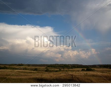 The Warm Summer Evening And A Rainbow Over The Fields And Forest That Emerged After The Recent Rain.