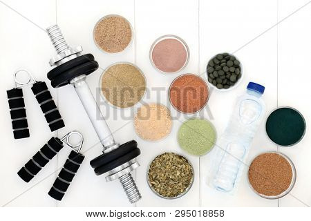 Body building equipment of weights and hand grippers, dietary supplement powders and chlorella tablets and with ginkgo green tea and fresh water. Top view. 