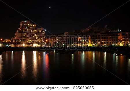 Dibba Al-Fujairah, Fujairah, UAE - April 8, 2019: Night view of Hotel Fairmont Fujairah beach resort and Mina Al Fajer buildings waterfront