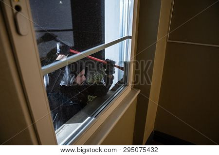 Thief Trying To Break The Window With Crowbar At Night