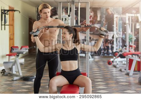 Strong Handsome Guy Helps Client Of Sport Hall To Use Fitness Station In Right Way, Choosing Suitabl