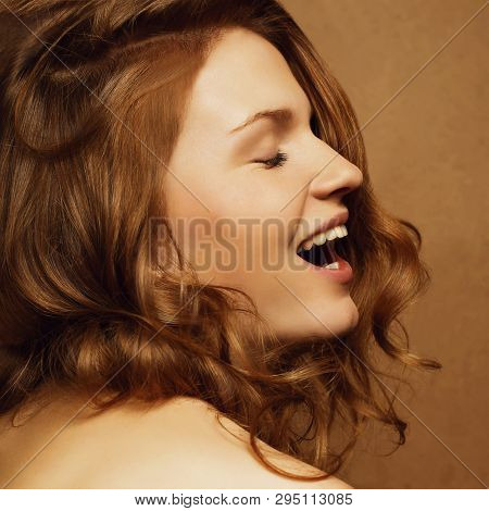Laughing Fashionable Model With Ginger Curly Hair On The Wooden Background. Studio Shot