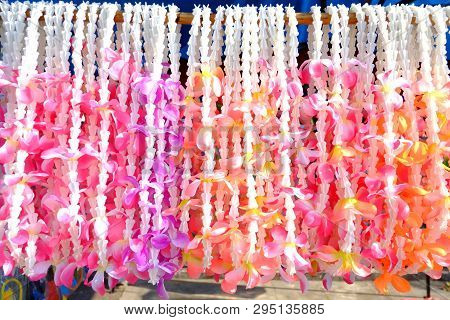 A Pile Of Multicolored Flower Garland Hanging From Wooden Rail And Selling In Outdoor Place For Song