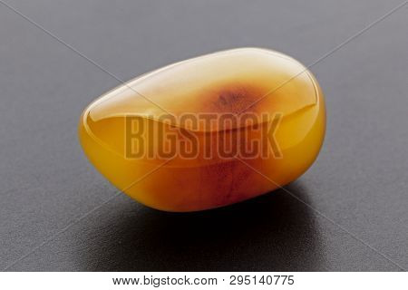 Natural Amber. A Piece Of Yellow Opaque Natural Amber On Dark Grey Background.