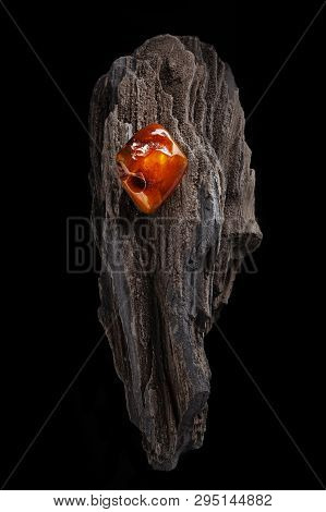 Natural Amber. A Piece Of Yellow And Red Semi Transparent Natural Amber On Piece Of Stoned Wood.