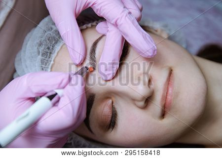 Permanent Makeup For Eyebrows. Microblading Brow. Beautician Doing Eyebrow Tattooing For Female Face