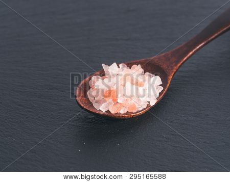 Himalayan Pink Salt In Spoon On Black Stone Background. Copy Space