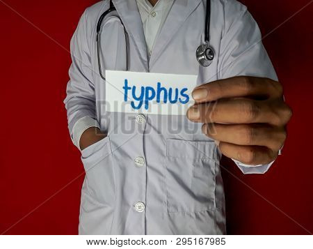 A Doctor Standing, Hold The Typhus Paper Text On Red Background. Medical And Healthcare Concept.